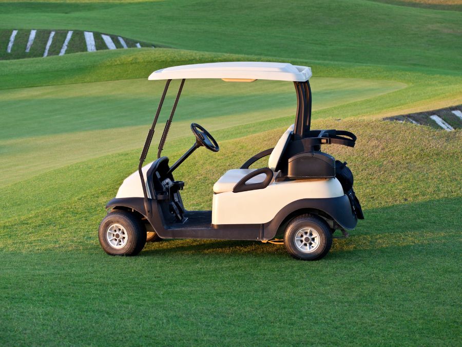 Golf cart parked on a well-manicured golf course with rolling green hills in the background.
