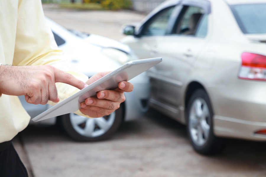 Insurance agent using a tablet while reviewing vehicles for auto insurance coverage.