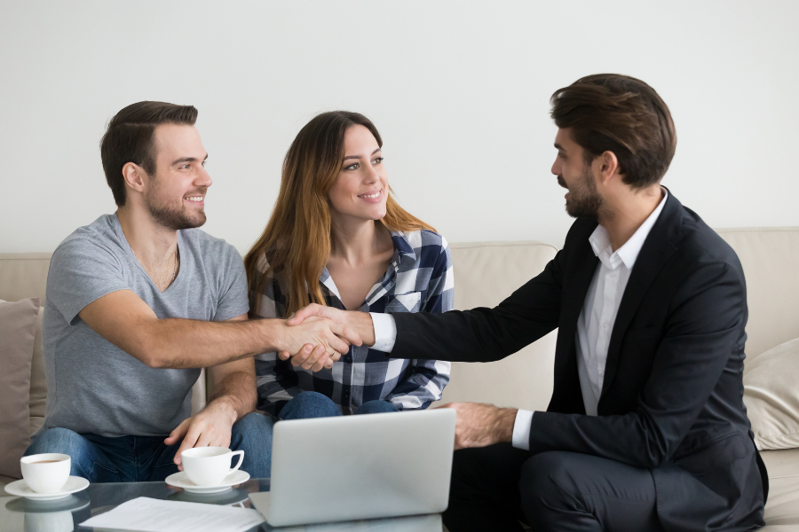 Insurance advisor shaking hands with a couple during a home insurance consultation.