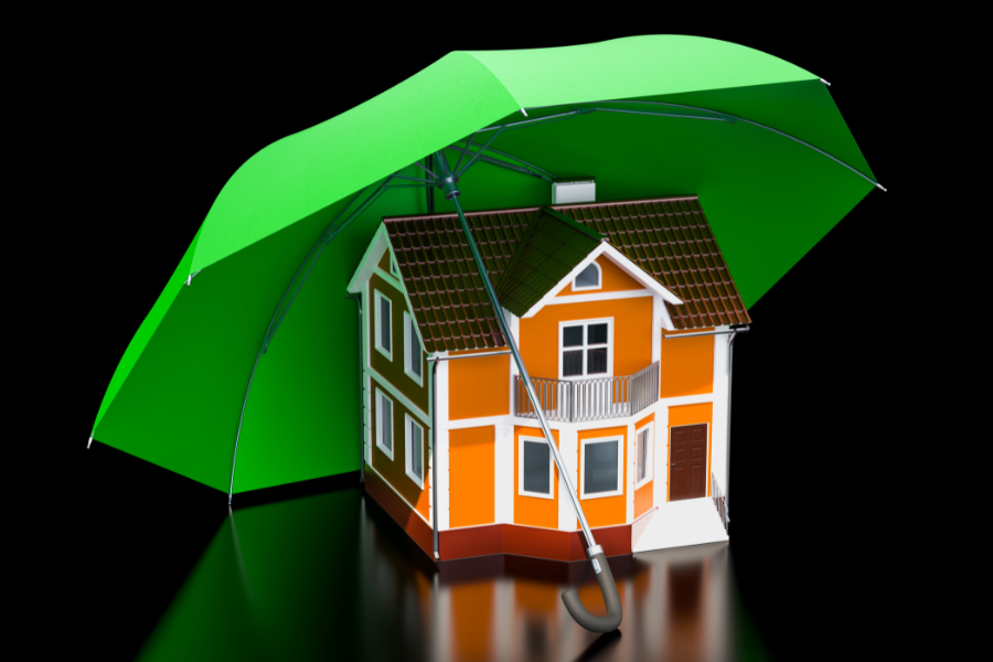Model house protected under a green umbrella, representing home insurance coverage and protection.
