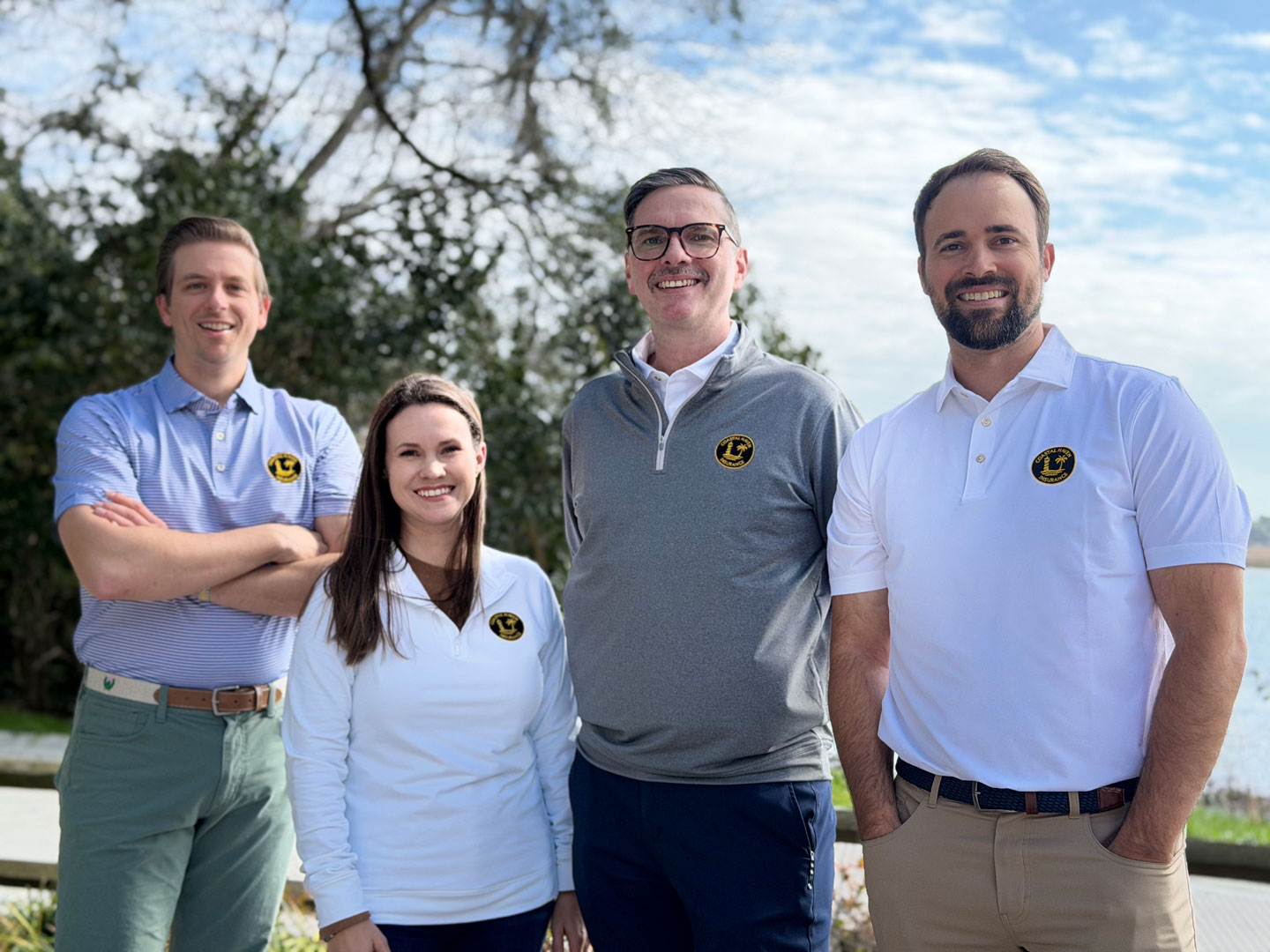 Four insurance team members wearing branded shirts standing outdoors.