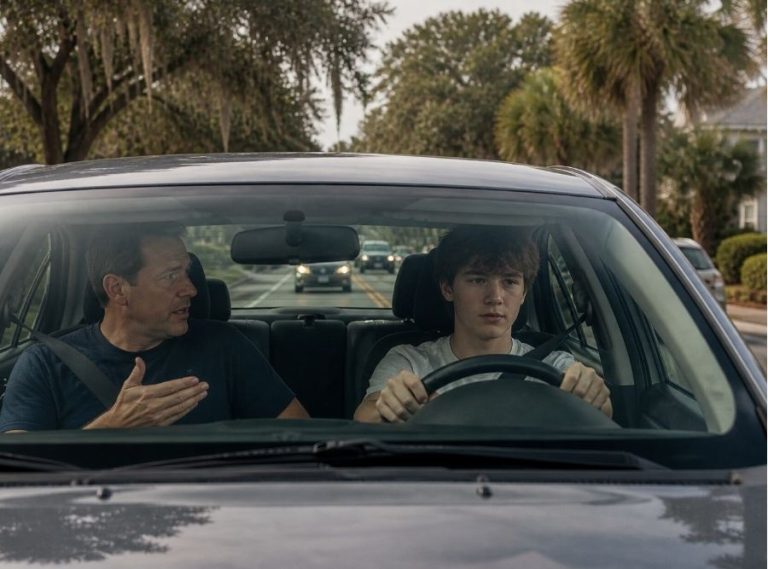 A realistic suburban Bluffton, South Carolina scene showing a teenage driver practicing driving with a parent in the passenger seat inside a modern sedan. The car is traveling through a residential area near Buckwalter Parkway or New Riverside, with light traffic visible ahead. Surroundings include palm trees, moss-draped oak trees, and Lowcountry-style homes. The mood should feel slightly tense but natural, capturing the learning stage and risk of new drivers. Soft natural lighting, high-resolution, cinematic, photo-realistic style, no text overlay.