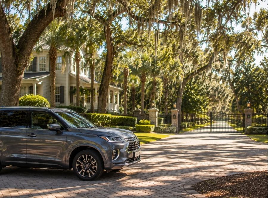 Luxury SUV parked in a gated Hilton Head Island plantation community with elegant Lowcountry homes, live oak trees, Spanish moss, and coastal landscaping.